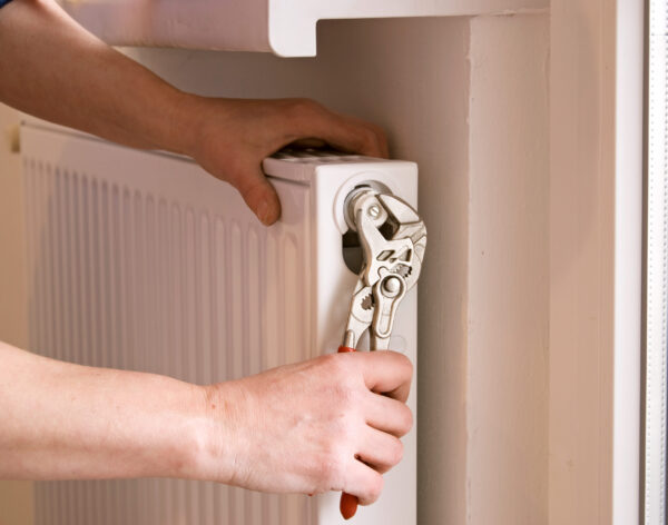 plumber fixing a radiator with pliers on a construction site
