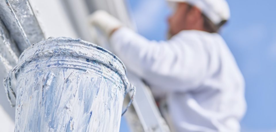 A person in white is painting the exterior of a house using a ladder and a bucket on the roof, in a close-up view. --ar 1:1 --profile hkenas3 --v 7 Job ID: 6293bf11-b692-48dc-bdb0-199437ff9c50